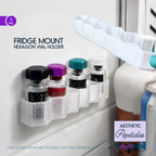 A white refrigerator-mounted hexagon vial holder shown holding several small medicine-style vials, with a matching holder floating above and text reading 'FRIDGE MOUNT HEXAGON VIAL HOLDER.' The scene is a real fridge environment with other objects partially visible, so this is Lifestyle rather than Product/Packaging.